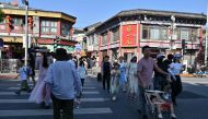 People cross a street in Beijing on August 29, 2024. (Photo by ADEK BERRY / AFP)