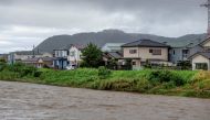 Muddy waters of the Kaneme River flow past houses lined up behind the river's bank in the aftermath of Typhoon Shanshan in Hiratsuka City, Kanagawa prefecture on August 30, 2024. Photo by Kazuhiro NOGI / AFP.