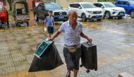 A local resident carries food and his luggage to a temporary shelter in a primary school ahead of the expected landfall of Super Typhoon Yagi in Wenchang, in southern China's Hainan province on September 6, 2024. (Photo by CNS / AFP) / China OUT