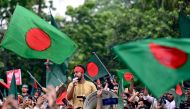 A student shouts slogans as demonstrators wave Bangladesh's national flag during Martyr March, a rally organised by Students Against Discrimination to mark one month to the ousting of the country's former Prime Minister Sheikh Hasina, in Dhaka on September 5, 2024. Photo by Munir UZ ZAMAN / AFP.