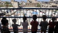 Children stand behind the rail of a hallway balcony outside classrooms sheltering people displaced by conflict at a school run by the UNRWA in Deir el-Balah in the central Gaza Strip on September 9, 2024. Photo by Eyad BABA / AFP