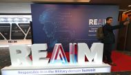 A participant takes a selfie in front of the logo of the Responsible AI in the Military Domain (REAIM) summit before its closing session in Seoul on September 10, 2024. (Photo by Jung Yeon-je / AFP)