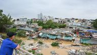 A man standing on Long Bien Bridge looks down at houses partially submerged in floodwaters in Hanoi on September 10, 2024, after typhoon Yagi hit Vietnam. Photo by Nhac NGUYEN / AFP