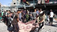 People use a blanket to transport a victim after an Israeli air strike hit a school in Nuseirat, in the central Gaza Strip on September 11, 2024. (Photo by Eyad Baba / AFP)