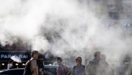 Pedestrians wait to cross a road as a cooling water mist is sprayed from nearby pipes in Busan on September 4, 2024. (Photo by ANTHONY WALLACE / AFP)
