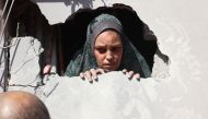 A Palestinian woman looks out through a hole in her home after an Israeli strike in the Shejaiya suburb east of Gaza City on September 12, 2024. (Photo by Omar Al-Qattaa / AFP)