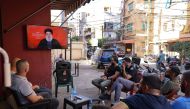 People watch on a television screen Hezbollah leader Hassan Nasrallah as he addresses the nation via video link, at a cafe in the Shiyah neighbourhood of Beirut's southern suburbs on September 19, 2024. (Photo by ANWAR AMRO / AFP)