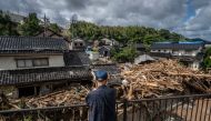 A man looks on as debris washed away from flooding is seen piled by houses along the Tsukada river following heavy rain in Wajima city, Ishikawa prefecture on September 23, 2024. Photo by Yuichi YAMAZAKI / AFP.