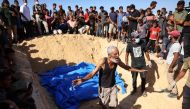 A man reacts as others gather to watch the burial of some of the 88 bodies in a mass grave in Khan Yunis on September 26, 2024. (Photo by Bashar Taleb / AFP)