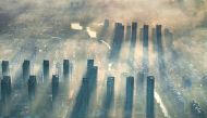 The aerial photo taken on September 25, 2024 shows a general view of sunlight shining through the mist above residential buildings in the morning in Lianyungang, in eastern China's Jiangsu province. (Photo by STRINGER / AFP) / CHINA OUT
