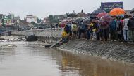 Residents stand along a street as they inspect flood waters after the Bagmati river overflowed during monsoon rains in Kathmandu on September 28, 2024. (Photo by Prakash Mathema / AFP)
 