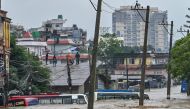 Residents climb over a rooftop as their neighbourhood submerged in flood waters in Kathmandu on September 28, 2024. (Photo by Prakash Mathema / AFP)