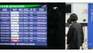 People stand next to a monitor showing flight status at Kaohsiung International Airport, with all flights cancelled as Typhoon Krathon nears in Kaohsiung on October 2, 2024. Photo by WALID BERRAZEG / AFP.