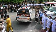 Police officers and nurses stand near media representatives as an ambulance carrying victims' remains leaves the forensic institute at the police hospital in Bangkok, on October 2, 2024. Photo by Manan VATSYAYANA / AFP