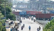 Commuters trace back from a street blocked with shipping containers by authorities for security measures against a protest in Lahore on October 5, 2024. (Photo by Arif Ali / AFP)