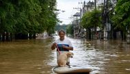 A resident transports his dog on a board as he wades through flood waters in Chiang Mai, on October 6, 2024. Photo by AFP.