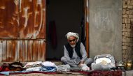 An Afghan vendor selling clothes waits for customers along a street on the outskirts of Mazar-i-Sharif on October 6, 2024. (Photo by Atif Aryan / AFP)
