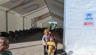 Children play around an emergency services tent set up at the Jdeidat Yabus border crossing in southwestern Syria as displaced people arrive from Lebanon on October 7, 2024. (Photo by LOUAI BESHARA / AFP)
