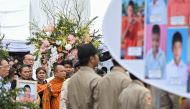 Grieving family members hold portraits of their loved ones during the cremation ceremony for the victims of a school bus fire, which marks the last Buddhist funeral rites at Wat Khao Phraya Sangkharam School in Uthai Thani on October 8, 2024.