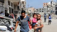 A man carries a child while evacuating in the Jabalia camp for Palestinian refugees in the northern Gaza Strip on October 9, 2024. Photo by Omar AL-QATTAA / AFP.
