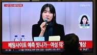 A person watches a news broadcast with file footage of South Korean author Han Kang, at a train station in Seoul on October 10, 2024. Photo by JUNG YEON-JE / AFP