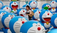 This picture taken on July 18, 2013 shows a journalist walking amid life-size figures of Doraemon during the press preview of the Fujiko F Fujio Exhibition in Tokyo. Photo by TORU YAMANAKA / AFP