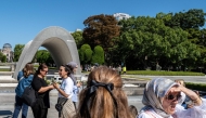 A group of tourists visits the cenotaph as the ruins of the Hiroshima Prefectural Industrial Promotion Hall, now commonly known as the atomic bomb dome (back), is seen from the Hiroshima Peace Memorial Park in Hiroshima city on October 12, 2024. (Photo by Philip FONG / AFP)