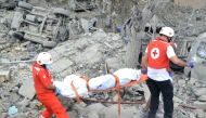 Paramedics with the Lebanese Red Cross transport a body unearthed from the rubble at the site of an Israeli airstrike that targeted the northern Lebanese village of Aito on October 14, 2024. (Photo by Fathi Al-MasriI / AFP)