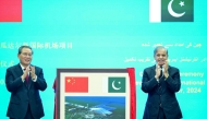 In this handout photograph taken on October 14, 2024, and released by Pakistan's Prime Minister Office, China's Premier Li Qiang (L) and Pakistan's Prime Minister Shehbaz Sharif gesture after unveiling a plaque to mark the completion of New Gwadar International Airport (NGIA) during a ceremony at the Prime Minister House in Islamabad. (Photo by Pakistan's Prime Minister Office / AFP) 