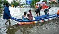 People ride a boat through a flooded street amid heavy rainfall in Chennai on October 16, 2024. (Photo by R.Satish BABU / AFP)