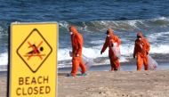 Workers in protective suits conduct a cleanup operation to clear petroleum-based 