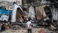 A Palestinian boy looks at destroyed shelters at the site of an Israeli airstrike which hit tents for displaced people two days earlier in the courtyard of Al-Aqsa Martyrs Hospital in Deir al-Balah in the central Gaza Strip on October 16, 2024. Photo by Eyad BABA / AFP.