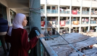 A displaced young Palestinian woman stares from a balcony inside UN school-turned-refuge in the Al-Shati refugee camp near Gaza City in the northern Gaza Strip, following a reported Israeli strike on October 19, 2024. (Photo by Omar Al-Qattaa / AFP)
 