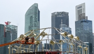 Photo used only for demonstration purposes. Workers stand on lifting platforms as they assemble the structure of a temporary construction near the financial business district in Singapore on October 14, 2024. Photo by Roslan RAHMAN / AFP.
