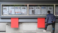 A man reads a newspaper displayed on a street for the public in Seoul on October 21, 2024, with coverage (in left case) on North Korea's decision to deploy thousands of soldiers to Ukraine's front lines. (Photo by Anthony WALLACE / AFP)
