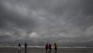 Dark clouds loom over the sea as local people and tourists walk along a beach in Digha, around 200km southwest of Kolkata, on October 24, 2024. (Photo by Dibyangshu SARKAR / AFP)