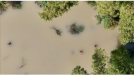 This picture shows an aerial view of people wading through a flooded area as they search for the body of a villager in Tuguegarao, Cagayan province, north of Manila on October 26, 2024. Photo by John DIMAIN / AFP