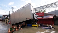 People wade through a flooded road brought about by Tropical Storm Trami, in Naga, Camarines Sur on October 25, 2024. (Photo by ZALRIAN SAYAT / AFP)