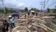 People walk amongst debris of logs swept away due to heavy rains brought about by Tropical Storm Trami in Laurel, Batangas province, south of Manila on October 25, 2024. Photo by Ted ALJIBE / AFP.