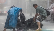 A man (R) helps a motorist with a scooter amid heavy rain due to Super Typhoon Kong-rey in Keelung on October 31, 2024. (Photo by I-Hwa Cheng / AFP)