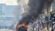 Flames engulf a military vehicle after clashes between protesters and the police in Mirpur on October 31, 2024. Bangladeshi garment workers furious at job layoffs in the economically vital sector clashed with police and soldiers on October 31, with two teenagers shot and wounded, officers said. (Photo by Md. Naimur Rahman / AFP)