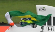 Mercedes' British driver Lewis Hamilton holds a Brazilian flag while driving the McLaren MP4-5B with which the late Ayrton Senna won his second Formula 1 world title in 1990 during a lap to mark the 30th anniversary of Senna's death at the San Marino Grand Prix, ahead of the Formula One Sao Paulo Grand Prix at the Jose Carlos Pace racetrack, aka Interlagos, in Sao Paulo, Brazil, on November 3, 2024. Photo by NELSON ALMEIDA / AFP.