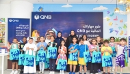 QNB officials pose for a group photo with participants during the Financial Literacy Autumn Camp for kids.