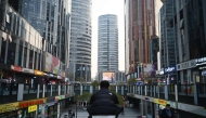 A man squats in a shopping mall in Beijing on November 8, 2024. (Photo by GREG BAKER / AFP)