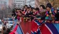 People (lower L) welcome members of the North Korean women's under-17 football team (R) on a street in Pyongyang on November 9, 2024. North Korea beat Spain on penalties November 3 in the Dominican Republic to clinch a record third Women's World Cup at under-17 level, adding it to their title in the under-20 version in September. (Photo by KIM Won Jin / AFP)
