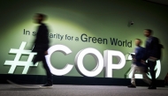 People walk past the logotype at the venue for the 2024 United Nations Climate Change Conference (COP29) in Baku on November 11, 2024. The COP29 climate talks open on November 11 in Azerbaijan, under the long shadow cast by the re-election of Donald Trump, who has pledged to row back on the United States' carbon-cutting commitments. Photo by Alexander NEMENOV / AFP.