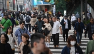 People cross a street in the Omotesando shopping area in Tokyo on November 15, 2024. (Photo by Yuichi YAMAZAKI / AFP)