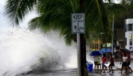 People (R) react as large waves break along a seawall ahead of the expected landfall of Super Typhoon Man-yi, in Legaspi City, Albay province on November 16, 2024. (Photo by CHARISM SAYAT / AFP)
