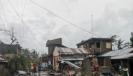 This handout photo released on November 17, 2024 through the courtesy of John Marshal Aquino Facebook page shows residents walking past destroyed houses in Panganiban town, Catanduanes province, after Super Typhoon Man-yi hit the province. Super Typhoon Man-yi uprooted trees, brought down power lines and ripped off corrugated iron roofing as it swept across the storm-weary Philippines on November 17, following an unusual streak of violent weather. (Photo by John Marshal Aquino / John Marshal Aquino / AFP)