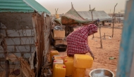 A woman pours water from a jerry can, in the Tarhil district, in Nouakchott, on September 30, 2024. (Photo by Michele Cattani / AFP)